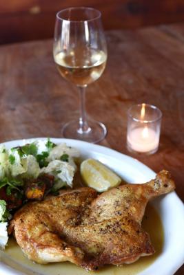 Brick chicken dinner with a glass of white wine